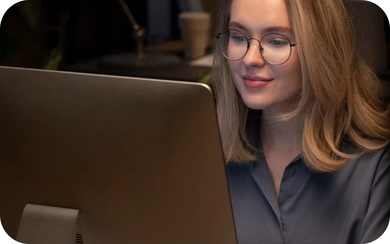Fotografia de uma mulher loura olhando para a tela do computador