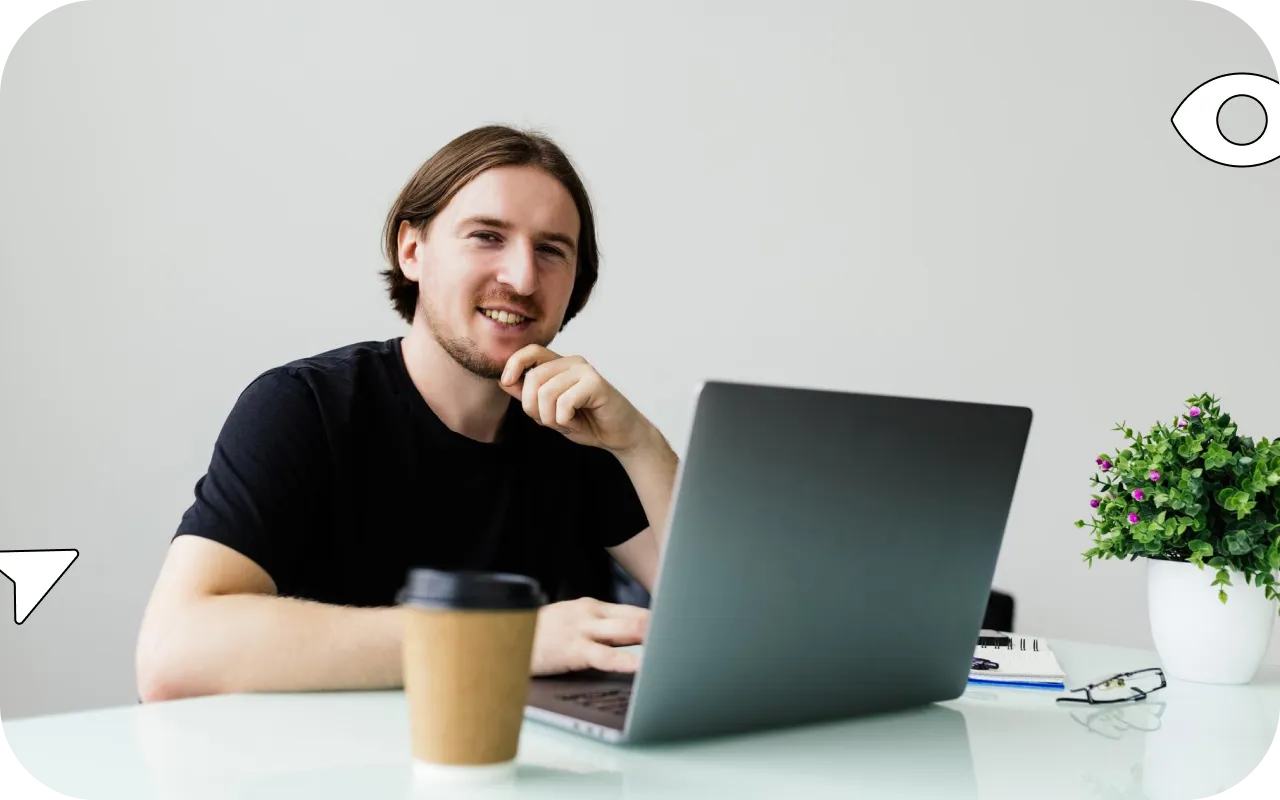 Fotografia de um homem com um copo de café em frente a um notebook